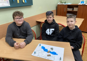 Uczniowie klasy piątej pokazują makietę Narnii z rzeką i zaśnieżonym krajobrazem wykonanym z materiałów plastycznych.