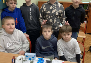 Uczniowie klasy piątej prezentują makietę Narnii z rzeką, budynkami i zimową scenerią.