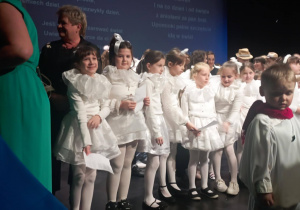 Uczennice klasy 2b w strojach aniołów stoją na scenie przed rozpoczęciem występu.