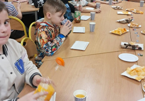 Uczniowie przy stolikach podczas wspólnego poczęstunku.