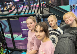 Uczennice stoją przy ściance wspinaczkowej w parku Hopa Lupa.