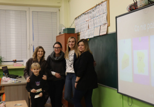 Cztery nauczycielki i uczeń stoją obok tablicy multimedialnej w klasie.