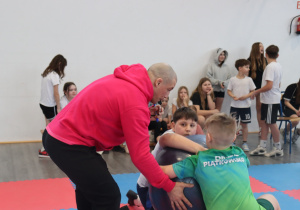 Damian Janikowski pokazuje uczniom technikę ćwiczenia z piłką podczas zajęć sportowych.
