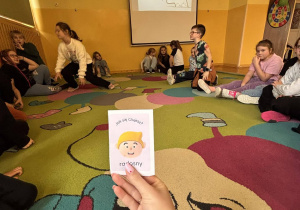 Karta z emocją „radosny” trzymana podczas zajęć o emocjach w świetlicy.