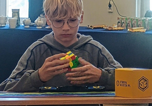 Uczeń układa kostkę Rubika podczas rundy konkursowej.