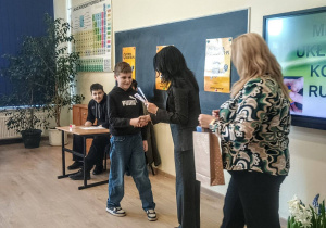 Uczeń odbiera dyplom podczas szkolnego konkursu „Mistrz układania kostki Rubika”.
