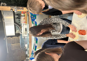 Uczniowie klasy VIIa przygotowują pizzę podczas warsztatów kulinarnych.