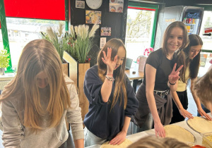 Uczniowie klasy VIIa uczą się formować pizzę z przygotowanego ciasta.