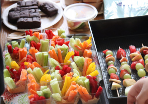 Zbliżenie na zdrowe przekąski: pokrojone warzywa i owocowe szaszłyki ułożone na stole.