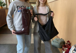 Dwie uczennice trzymają książki w kaloszu i torbie materiałowej.