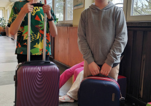 Dwóch uczniów trzyma walizkę i torbę zamiast plecaków.