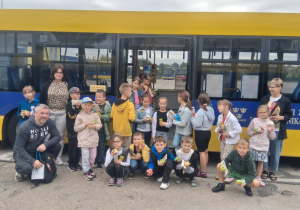 Uczniowie klasy 2B z SP13 z nauczycielkami Moniką Juran‑Tłoczek i Moniką Mettler pozują przed autobusem MZK w Pabianicach po zakończonej wycieczce, trzymając soczki i jabłka.