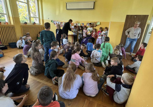 Dzieci siedzące w świetlicy podczas ogłoszenia wyników konkursu plastycznego.