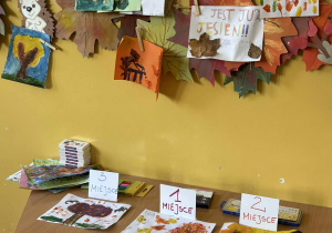 Zbliżenie na nagrodzone prace plastyczne przedstawiające jesienne drzewa.