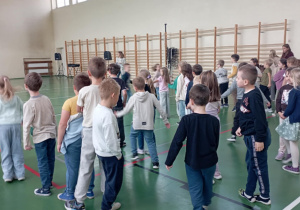 Dzieci ustawione w rzędach na sali gimnastycznej podczas integracyjnej zabawy ruchowej z okazji Dnia Integracji.