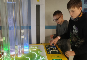 Dwóch uczniów obsługuje interaktywne stanowisko z mapą i podświetlanymi rurami w Centrum Nauki EC1.