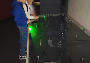 Uczniowie eksperymentują z laserem i zwierciadłami w centrum nauki.