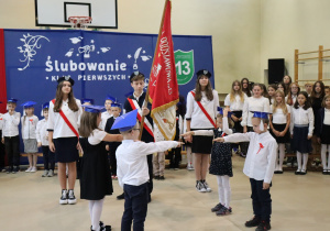 Pierwszoklasiści składają ślubowanie przed pocztem sztandarowym szkoły podczas uroczystości w SP 13.