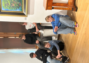 Chłopcy z klasy 7a siedzą swobodnie w sali muzeum po prelekcji podczas wystawy Kislinga w Pabianicach.