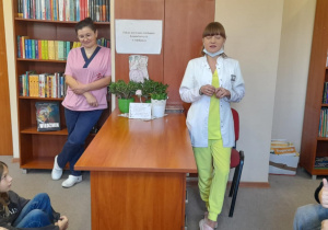 Uczniowie klasy 6a rozmawiają z panią stomatolog i asystentką w szkolnej bibliotece.