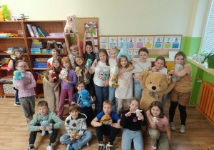 „Uczniowie klasy 3b w sali lekcyjnej prezentują swoje pluszowe misie i inne maskotki z okazji Dnia Pluszowego Misia.”