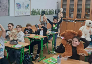„Uczniowie klasy 4a w sali lekcyjnej prezentują pluszowe misie i maskotki podczas Dnia Pluszowego Misia.”