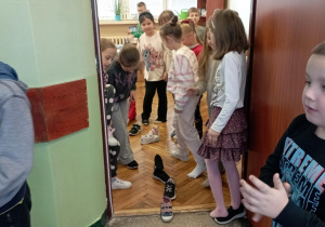 Dzieci z klasy 2b ustawiają buty w rzędzie w progu drzwi podczas andrzejkowej wróżby w sali lekcyjnej.