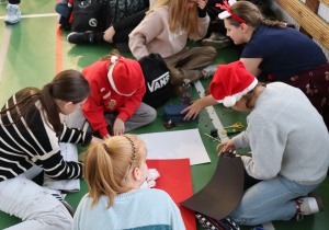 Uczniowie wykonują prace plastyczne podczas mikołajkowych zajęć kreatywnych.