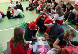 Uczniowie wykonują świąteczne prace plastyczne na sali gimnastycznej.
