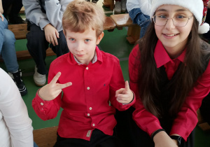 Uczniowie klasy czwartej siedzą na ławkach podczas szkolnej uroczystości.