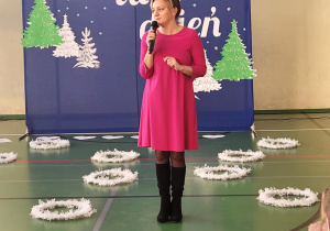 Pani dyrektor Anna Michalak składa świąteczne życzenia podczas koncertu świątecznego na sali gimnastycznej.