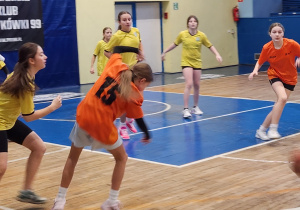 Zawodniczki w żółtych koszulkach podczas akcji meczowej w koszykówce dziewcząt.